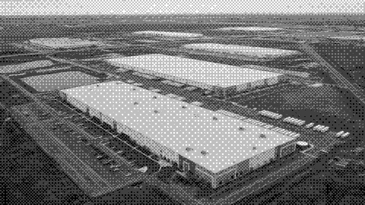 Aerial of large logistics warehouses on open land